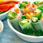 rice paper rolls with thai peanut sauce on blue board.