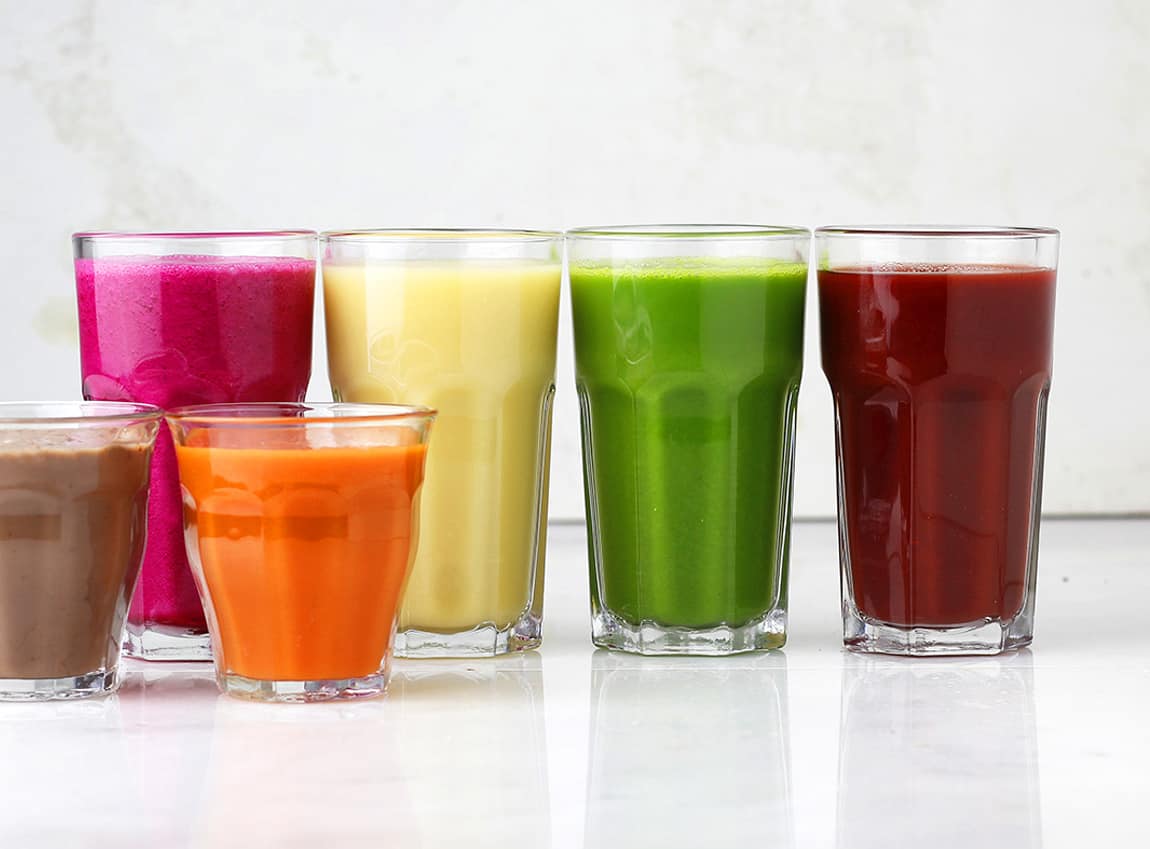 a row of colorful smoothies in glasses.