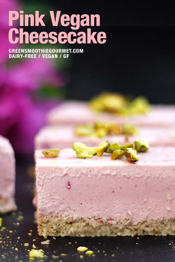 A pink vegan cheesecake recipe on a board with pink flowers behind it.