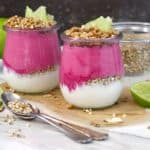 Two jars of dragon fruit lime smoothie on a layer of yogurt and sprinkling of buckwheat.