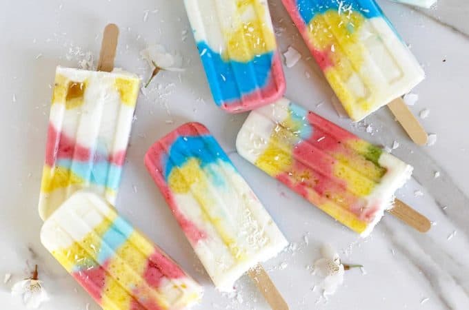 Rainbow popsicles on a white marble board.