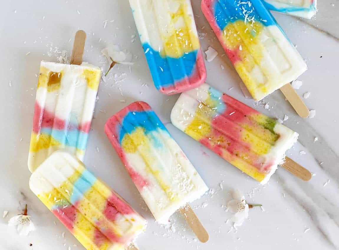 Rainbow popsicles on a white marble board.