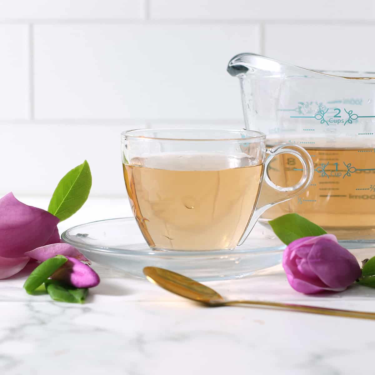 a cup of magnolia tea with petals on the table