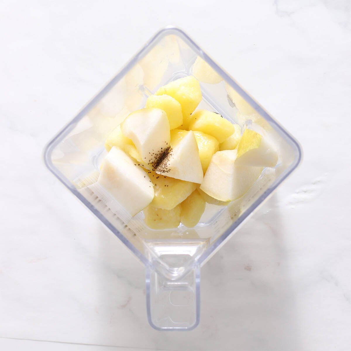 ingredients for a pineapple smoothie in a blender jar.