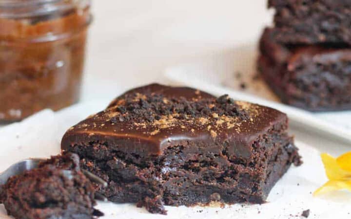 a brownie with a bite on a table with a jar of date paste