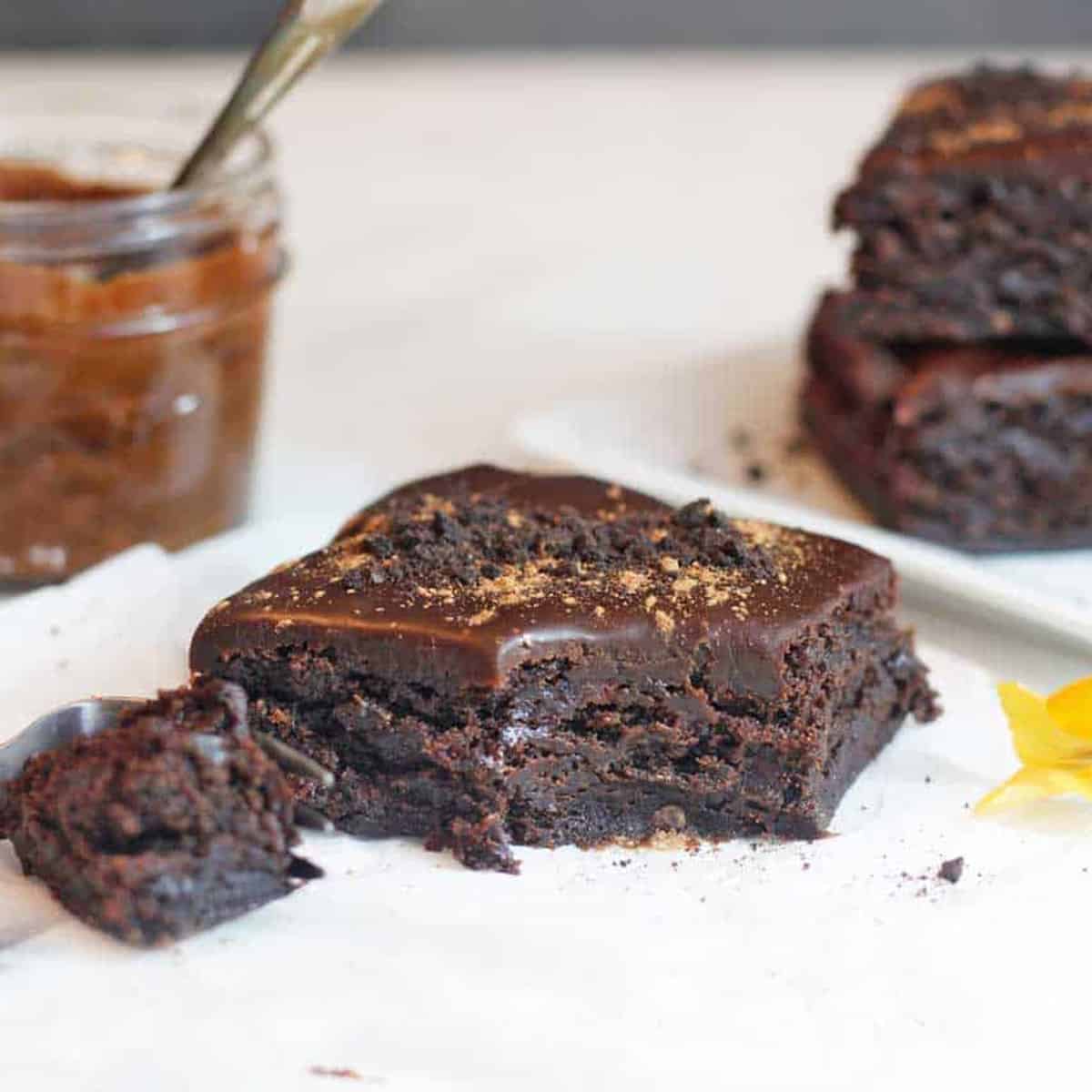 a brownie with a bite on a table with a jar of date paste