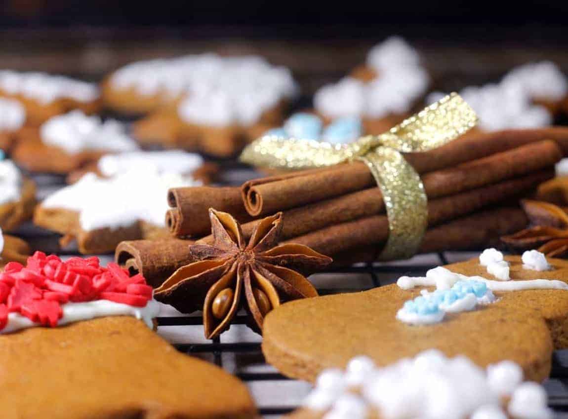 fresh cinnamon sticks wrapped in gold ribbon with anise star nearby on a black rack.