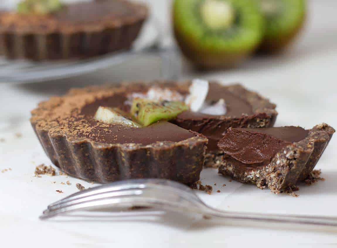 spicy dark chocolate vegan mini pies with kiwi behind it.