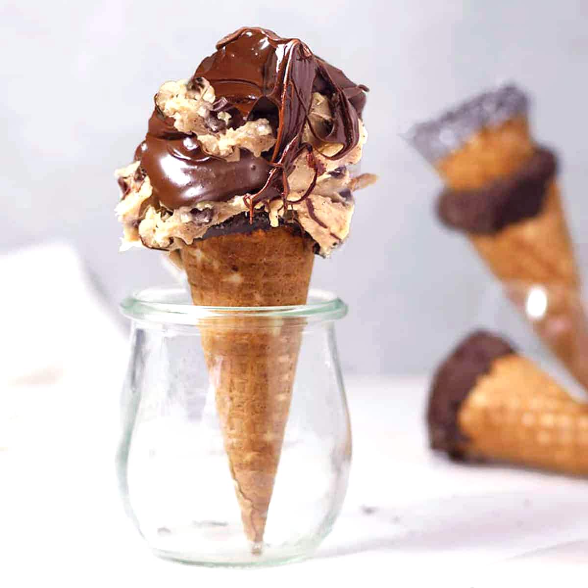 edible cookie dough in a cone with chocolate sauce.