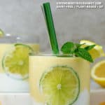 Lemon Smoothie Jackfruit in a glass with a lime slice inside the glass and lemon slices on table.