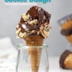 Healthy cookie dough piled in an ice cream cone and drizzled with chocolate and standing upright in a glass jar.