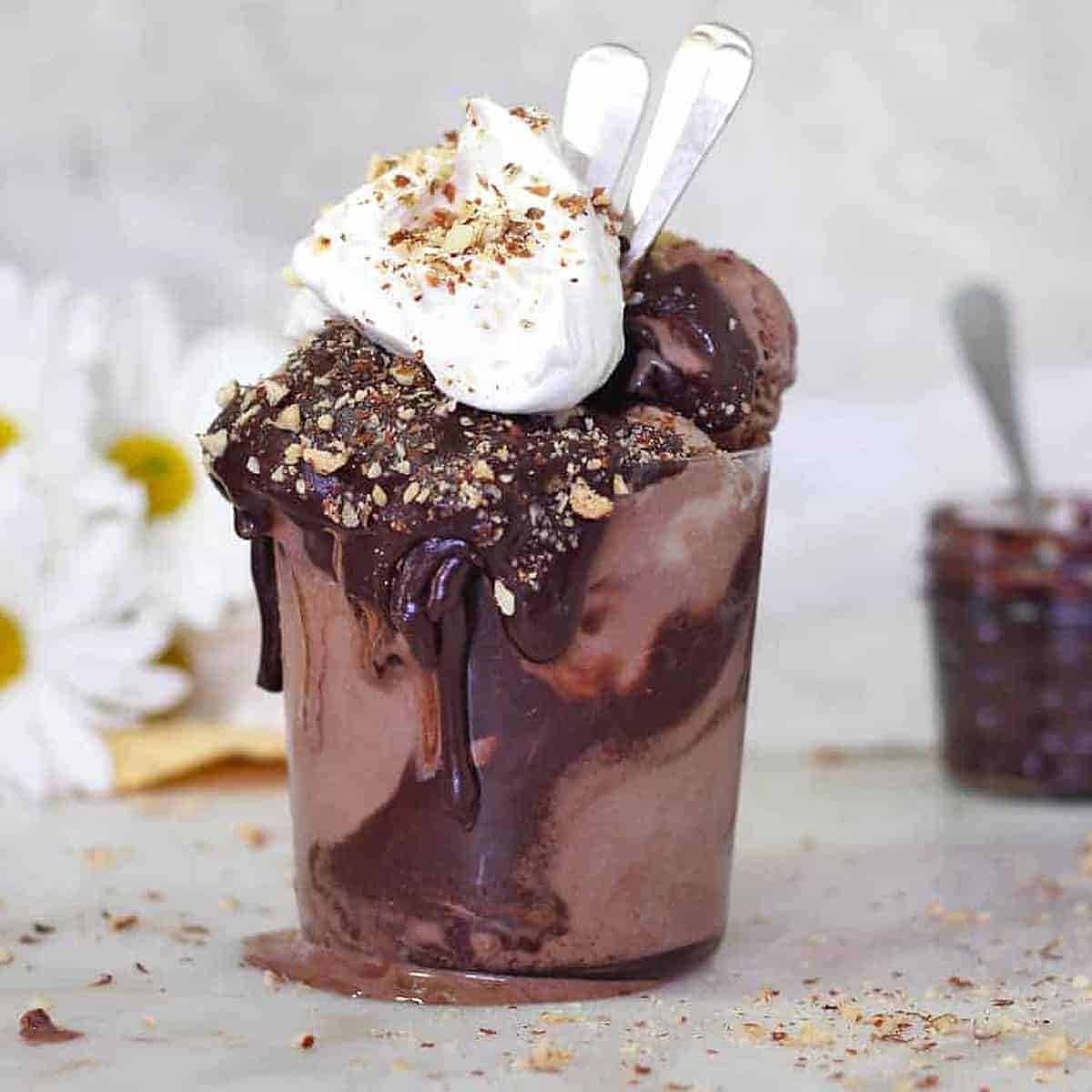 a jar of chocolate ice cream with whipped cream and chocolate syrup on top