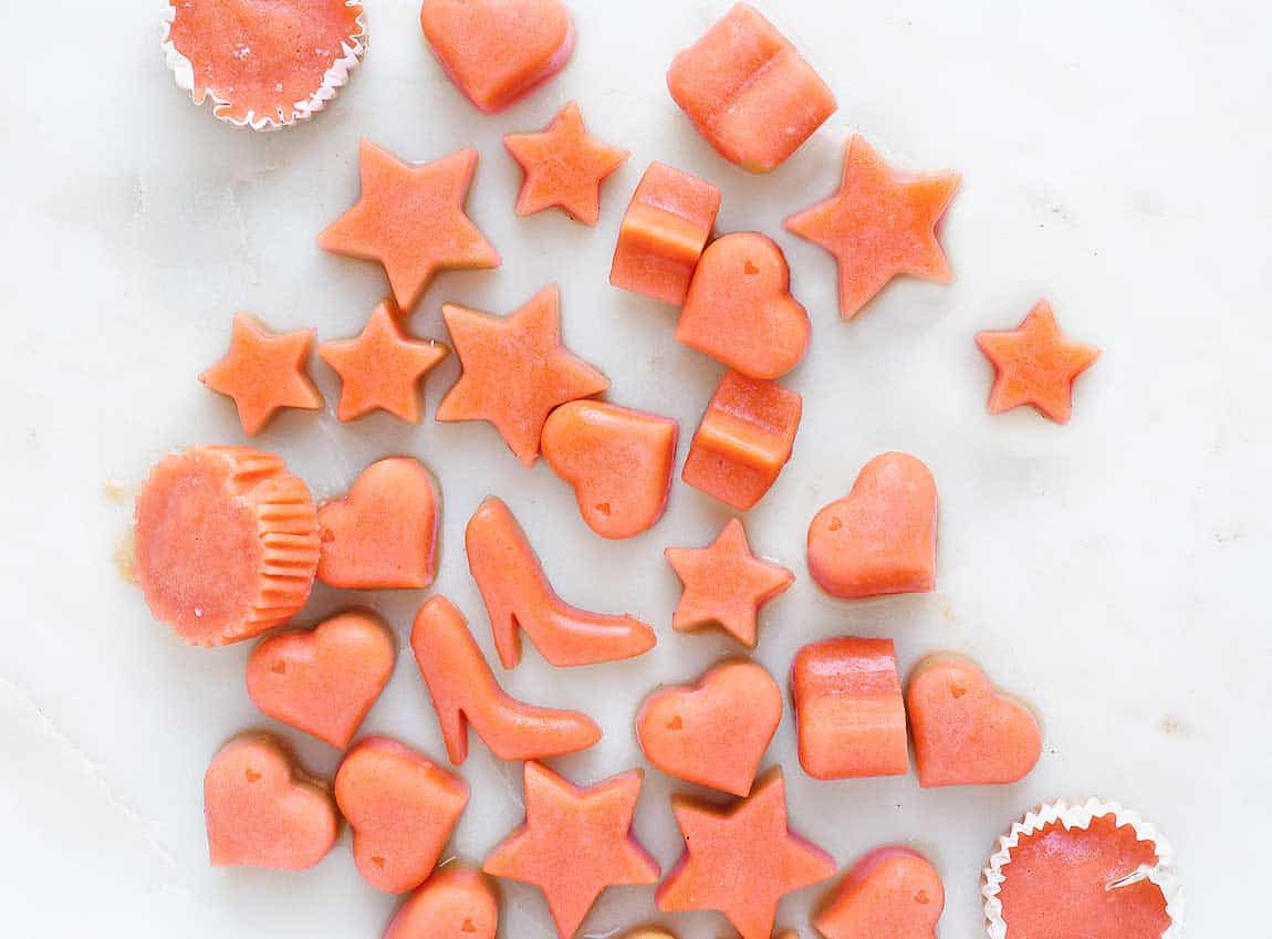 Cantaloupe carrot protein bites in shapes like shoes and stars on a white marble board.