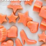 Cantaloupe carrot protein bites in shapes like shoes and stars on a white marble board.