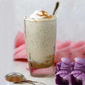 cashew milkshake in a glass with purple flowers