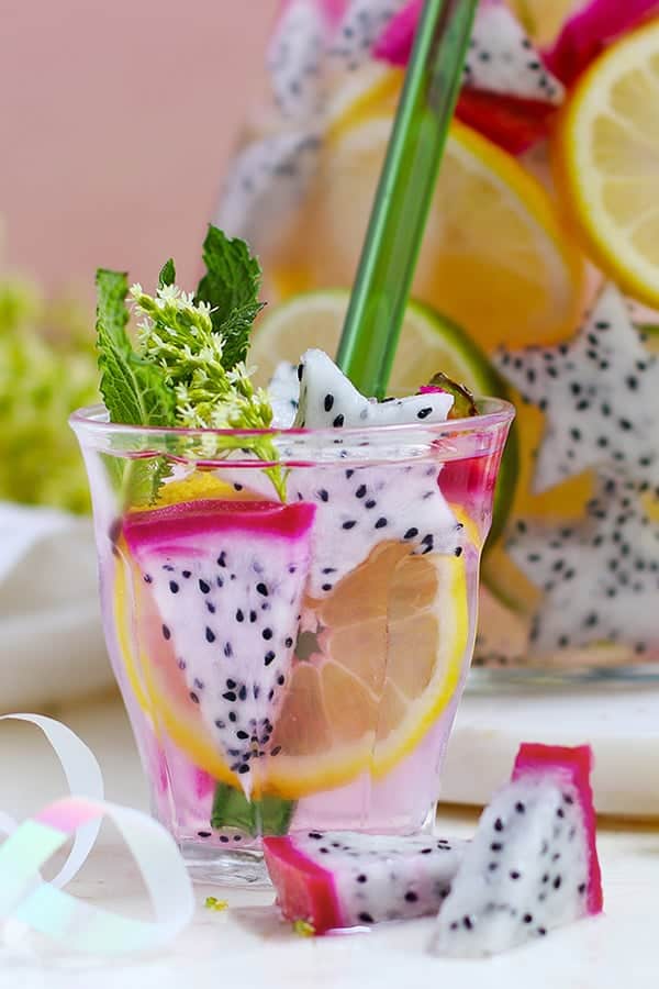 glass of pink infused water with slices of dragonfruit.