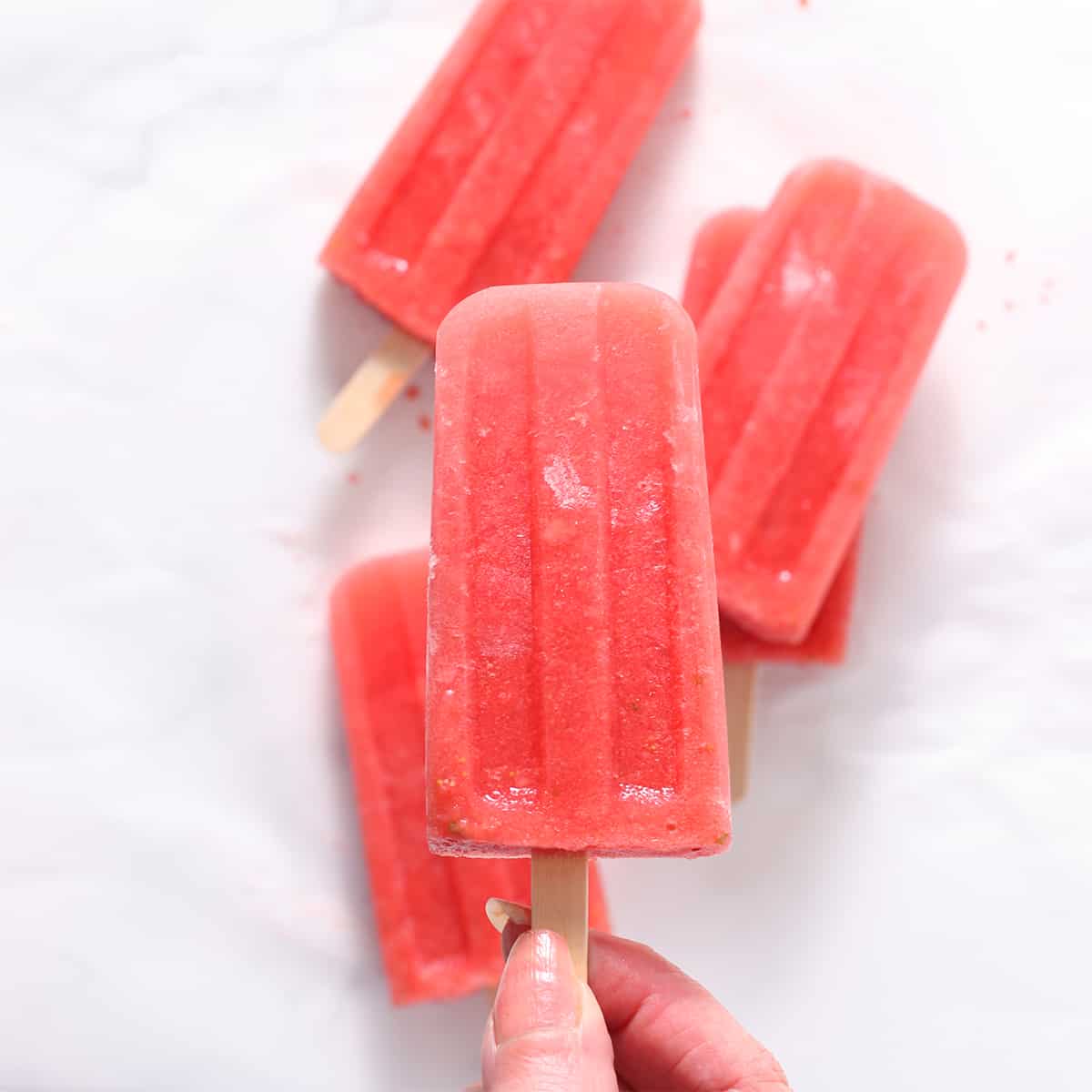 a hand holding a watermelon popsicle