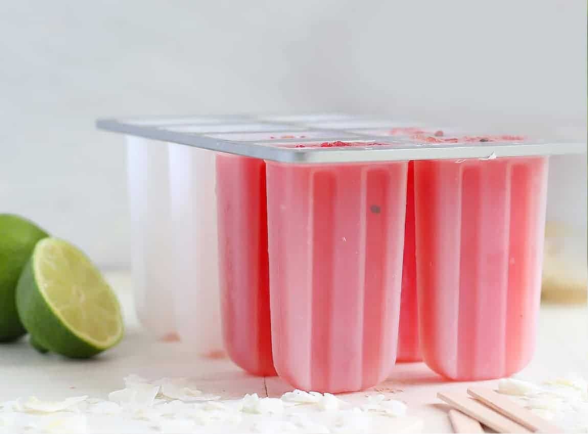 Four watermelon popsicles propped up in ice.