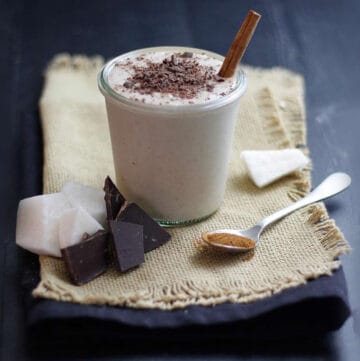jicama smoothie in a cup with chopped chocolate and chunks of jicama on a cloth