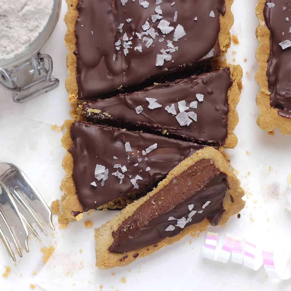 baked salted chocolate tart sliced with knife.