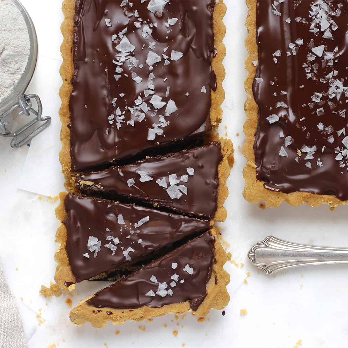 baked salted chocolate tart sliced with knife.