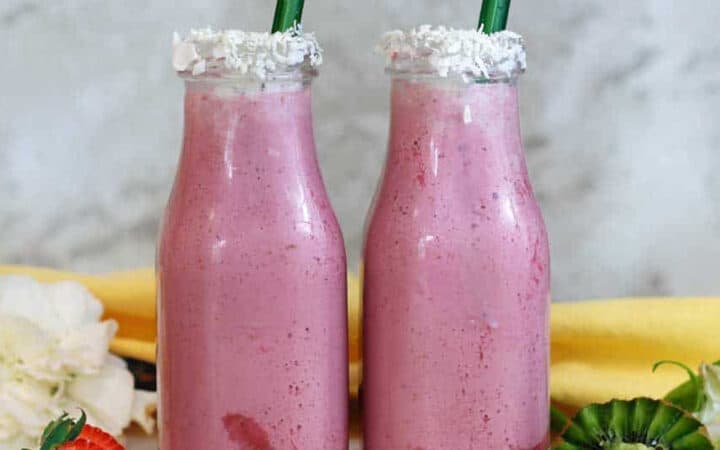 two bottles of cauliflower smoothie with a strawberry and a kiwi