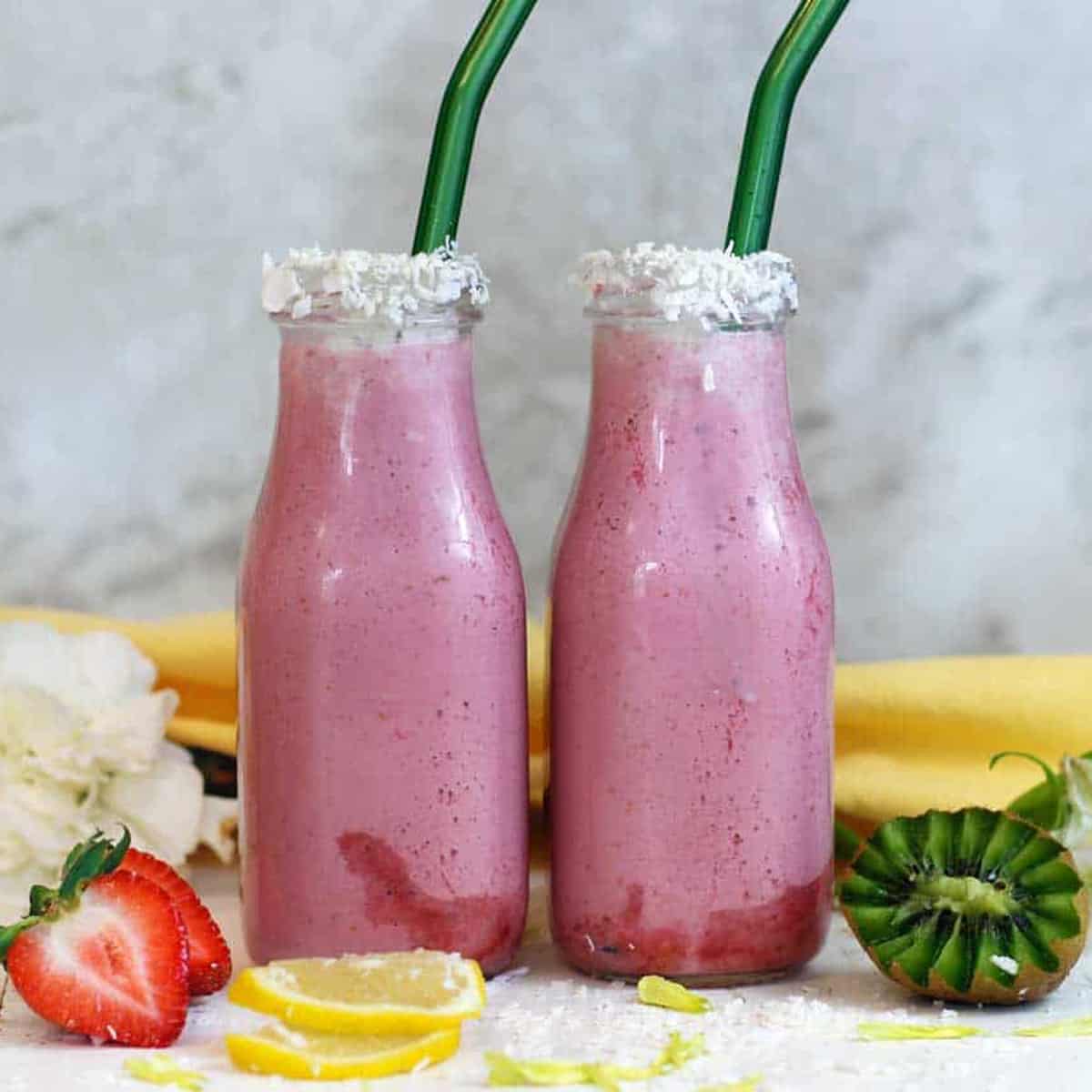 two bottles of cauliflower smoothie with a strawberry and a kiwi
