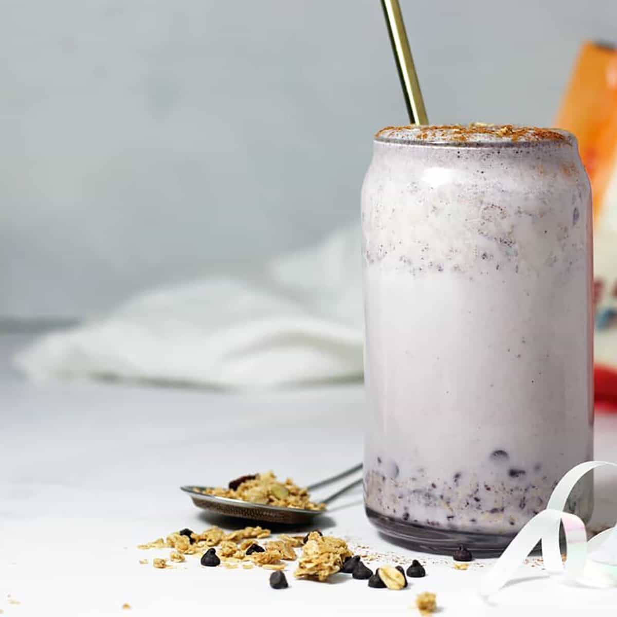 granola smoothie in a glass with a straw