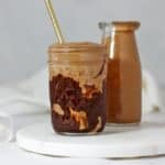 Peanut butter smoothie in a jar on a white plate.