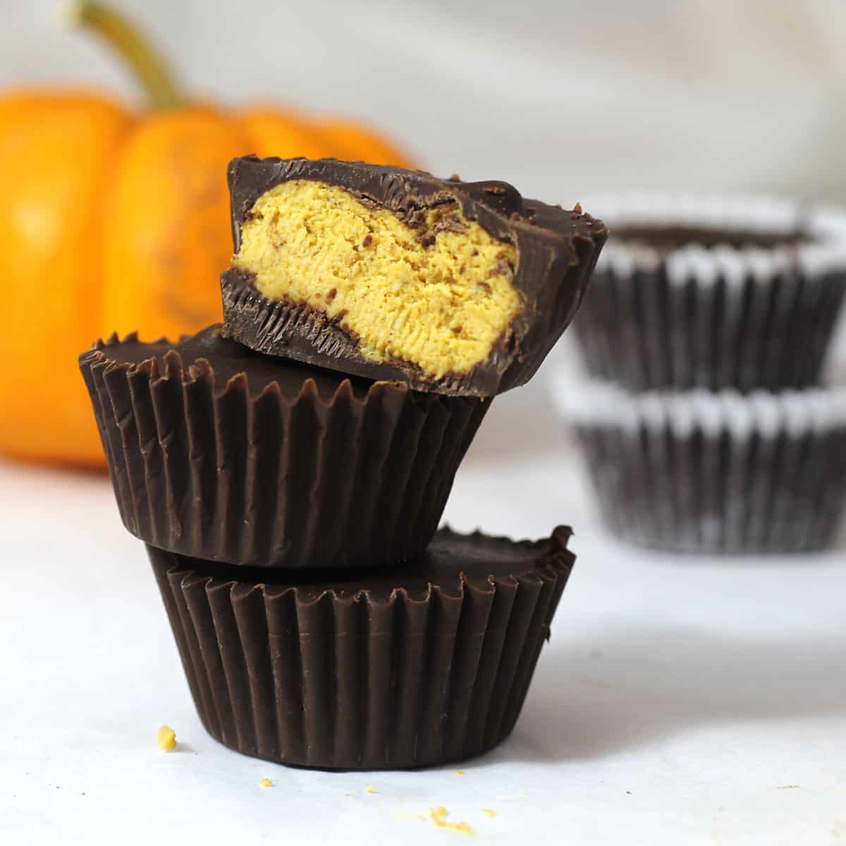 cups of pumpkin fudge coated in chocolate in a tower.