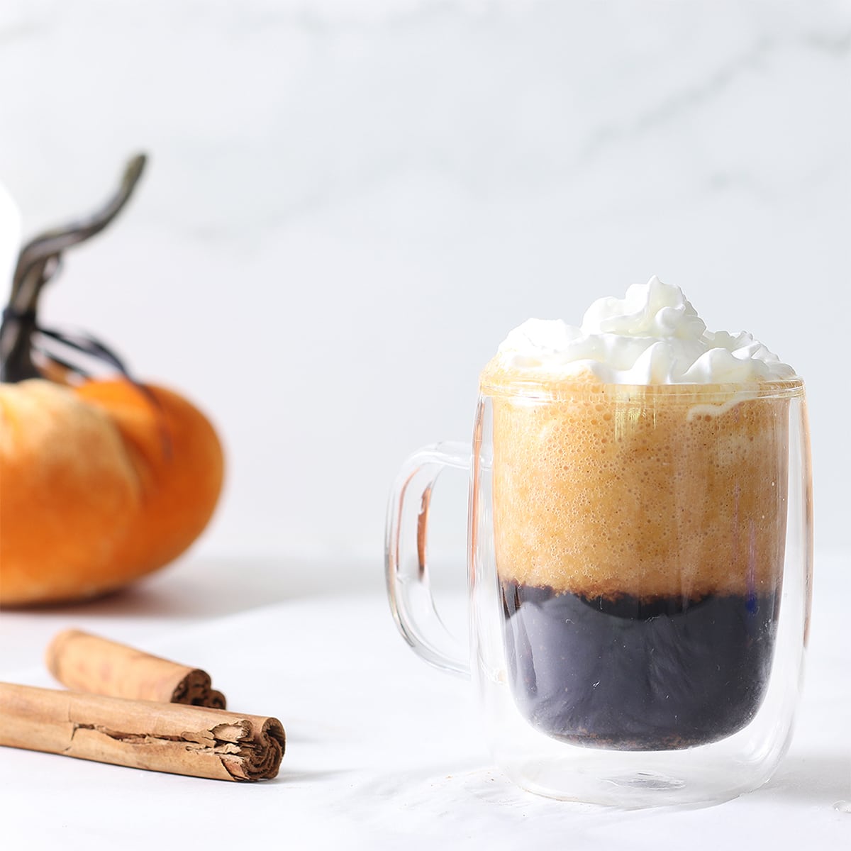 pumpkin spice latte in a mug with a pumpkin.