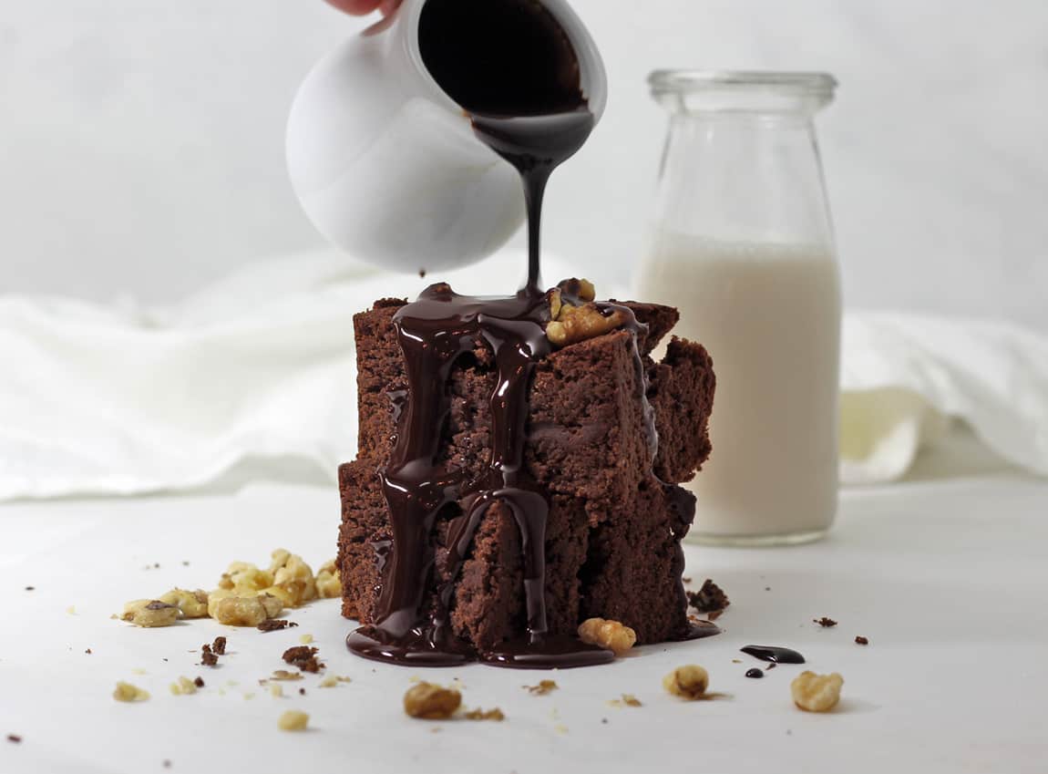 Shot of cake like brownies with hot fudge poured on top.
