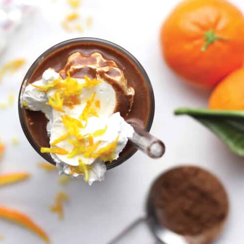 overhead shot of chocolate smoothie with cream inside and oranges on a board