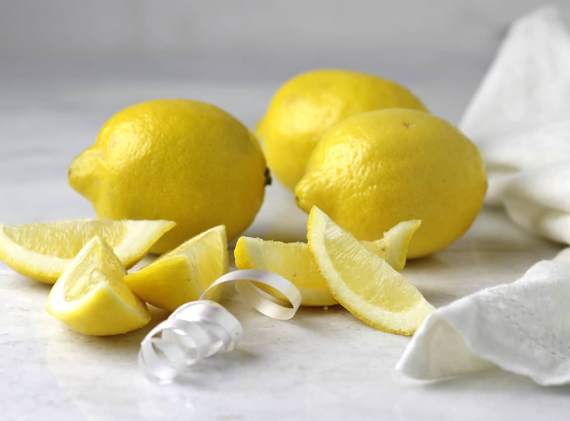 Fresh lemons whole and sliced ready on marble.