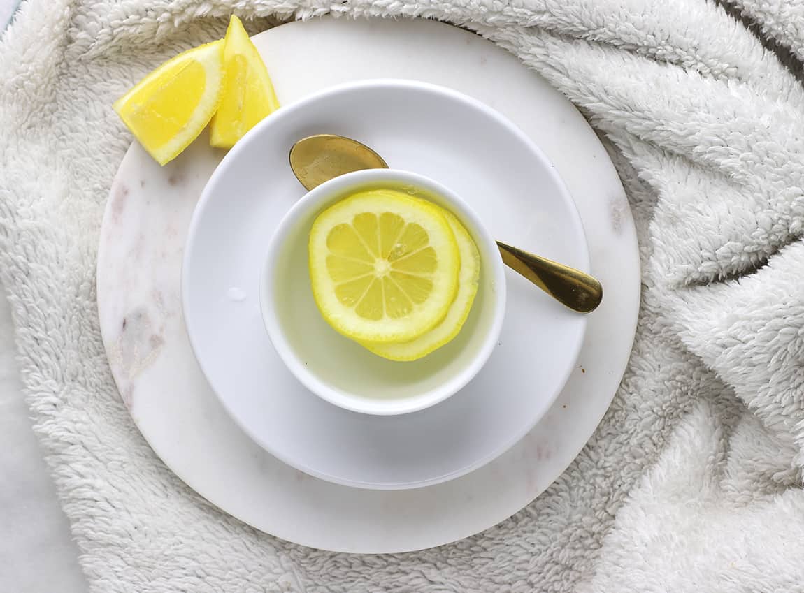 A warm cup of lemon water on a blanket.