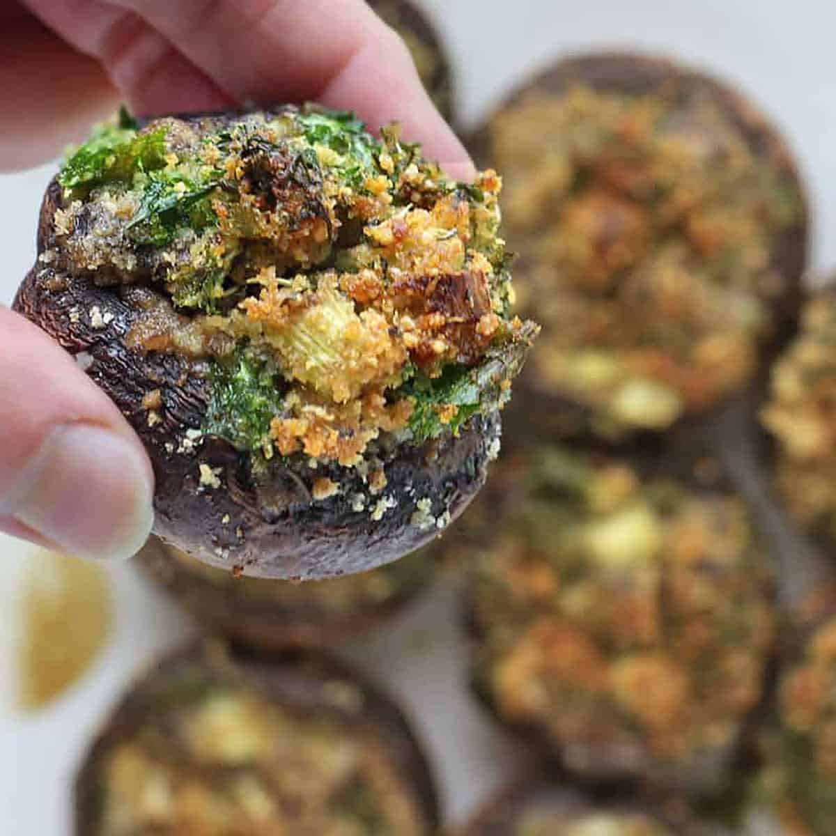 stuffed mushrooms in a platter in a stack and holding a hand.