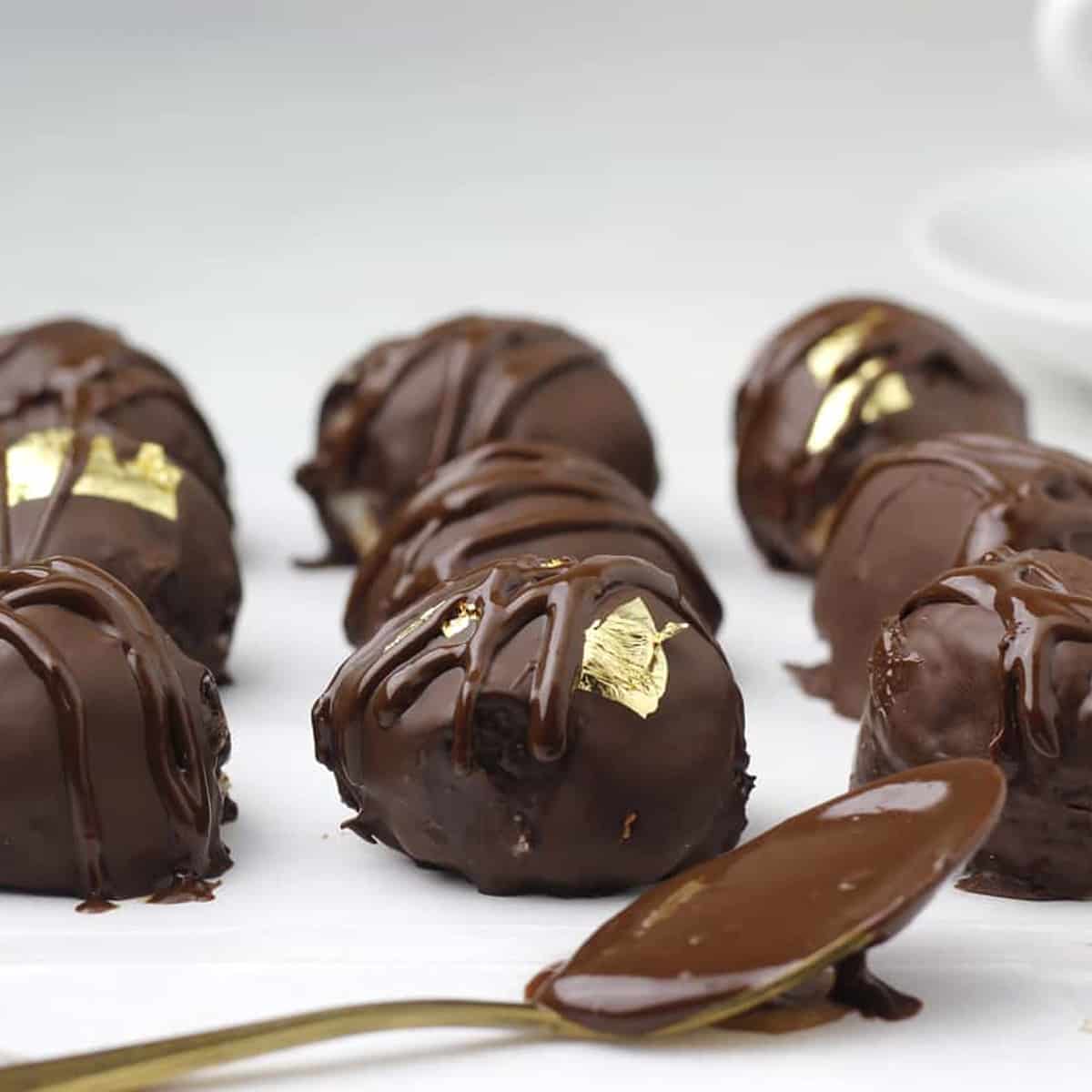 chocolate coconut balls in a row with a drizzle of chocolate