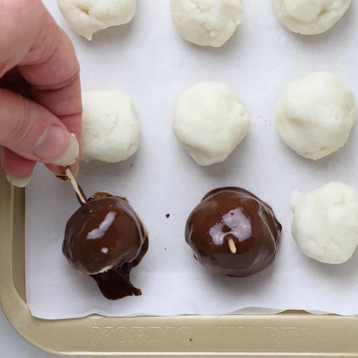 Dipping coconut truffles in melted chocolate.