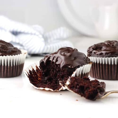 a chocolate cupcakes with a forkful take out and two cupcakes on either side