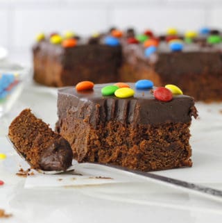Frosted Brownies with a bite out and rainbow sprinkles on white board.