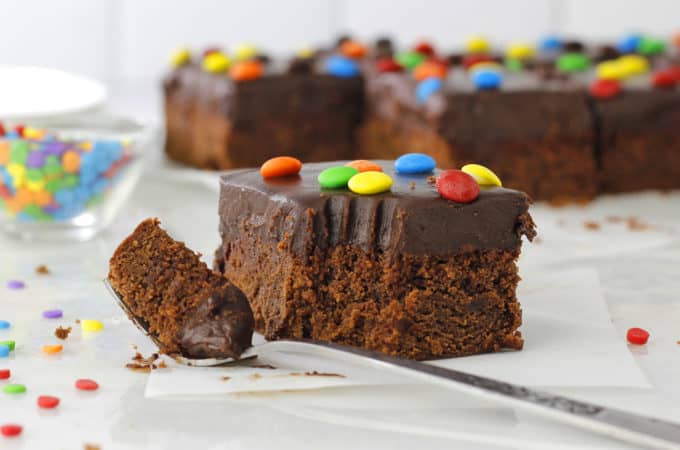 Frosted Brownies with a bite out and rainbow sprinkles on white board.