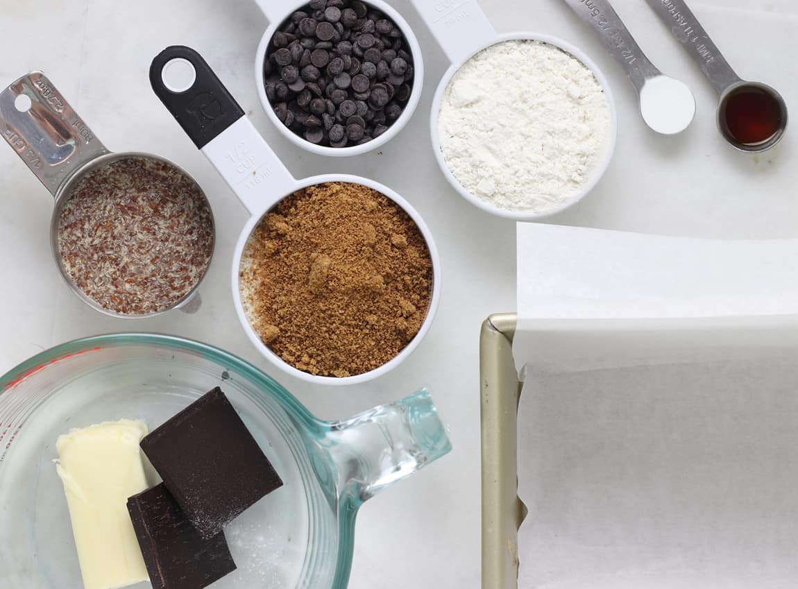 Ingredients of frosted brownies on white board.