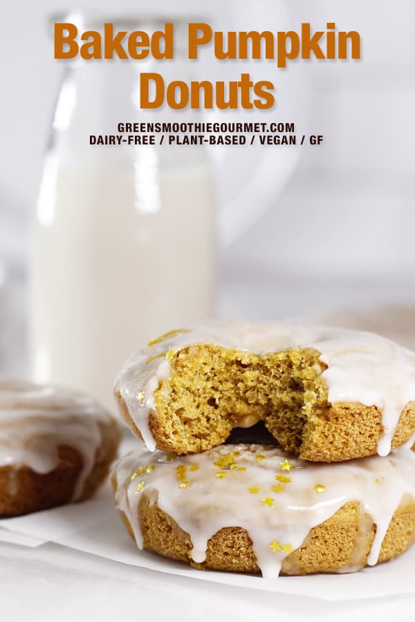 Glazed Pumpkin Baked Donuts with a bite taken out and a jug of milk in background.