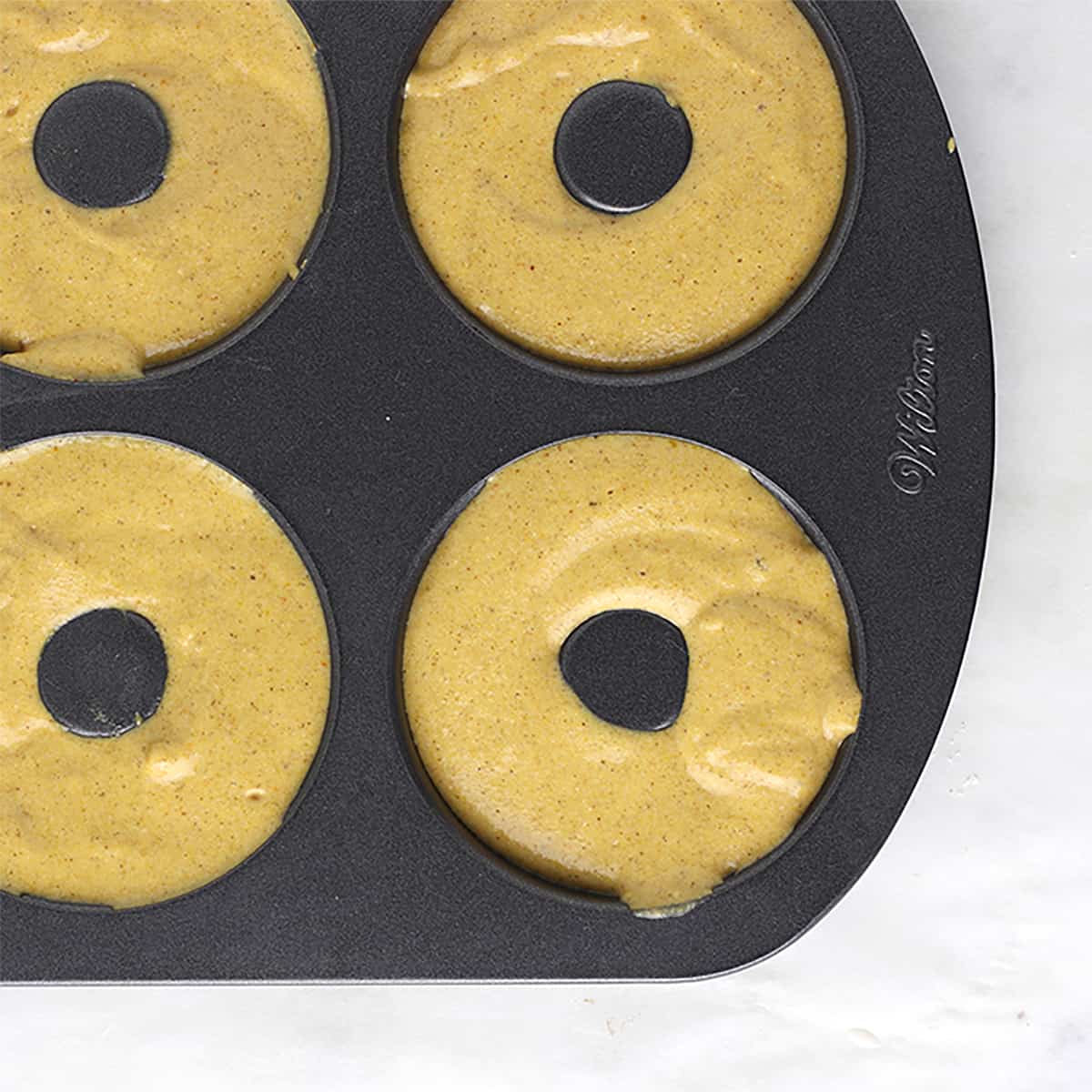 batter in donut pan for baked pumpkin donuts.