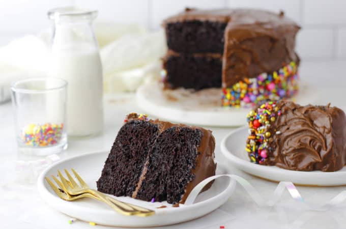Sliced chocolate cake with icing and sprinkles.