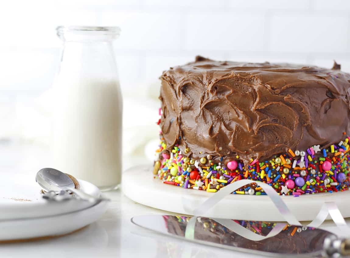 Sliced chocolate cake with icing and sprinkles.