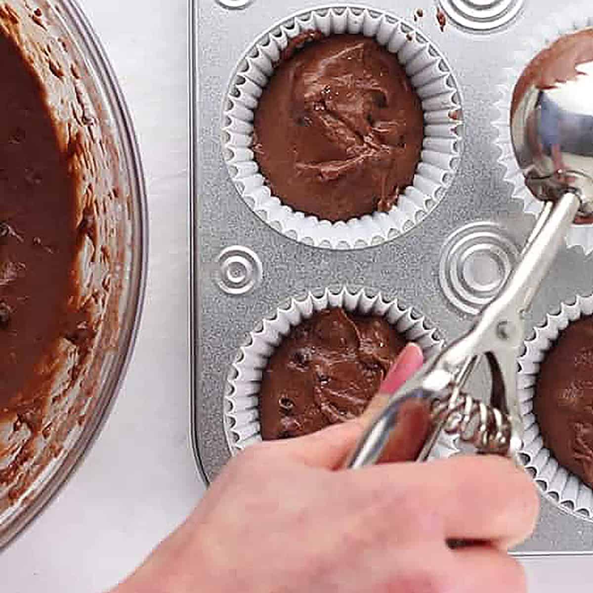 scooping chocolate pumpkin muffin batter.