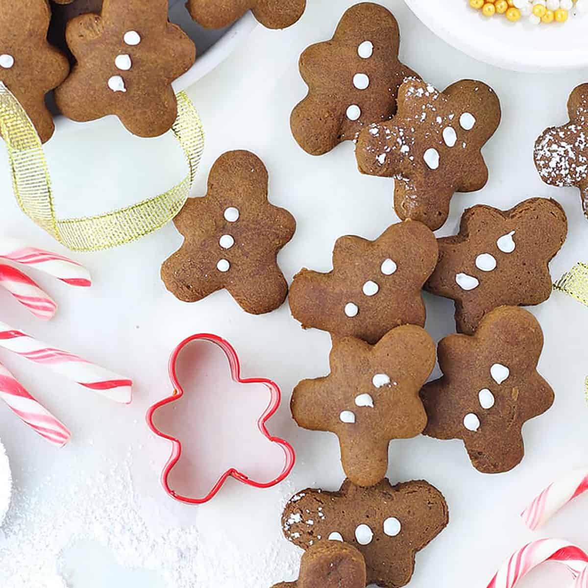 mini gingerbread men on a white board with a red gingerbread man cookie cutter.