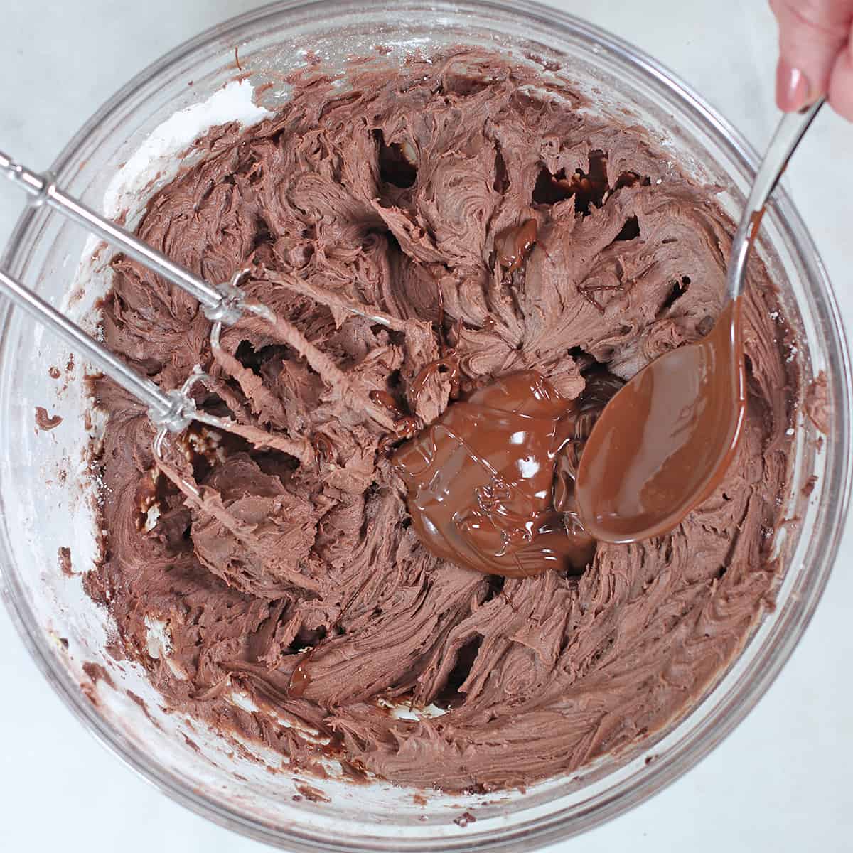 mixing fudge frosting in a bowl.