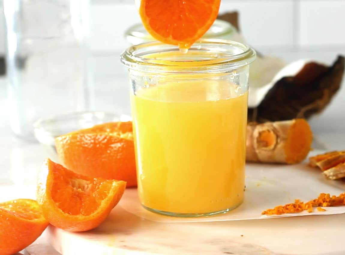 Orange juice being squeezed into a glass.